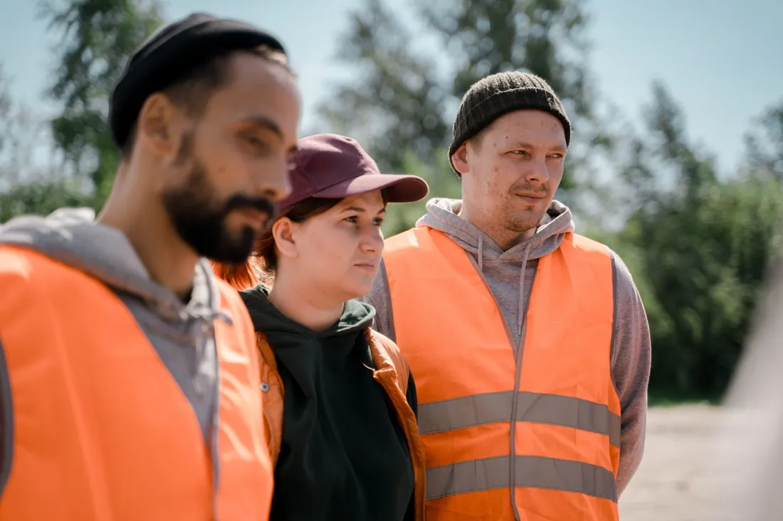 Drei Arbeiter in Warnwesten stehen vor dem Einsatz beieinander und sprechen den Tag durch