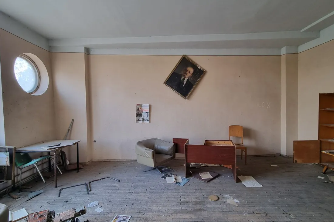 Verlassene Wohnung mit zurückgelassenem Bett, Tisch und Stühlen und Papieren auf dem Boden